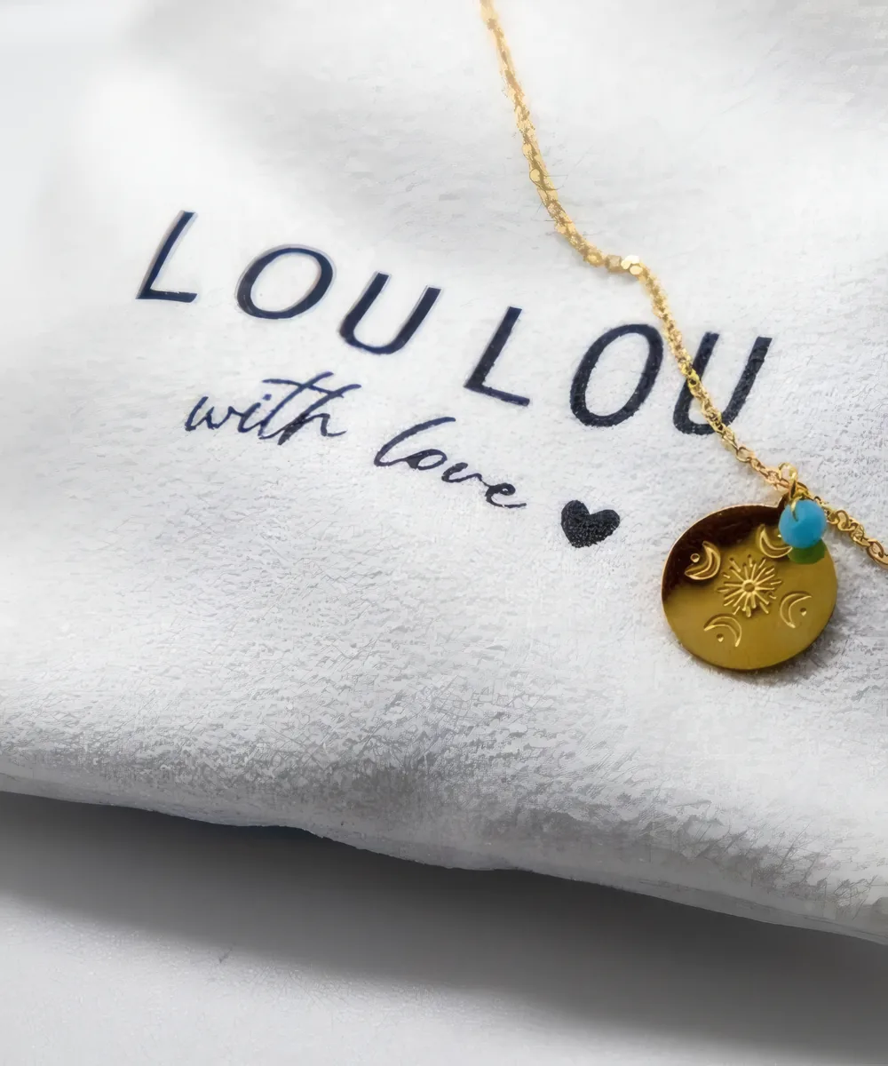 Collar con medalla de sol y lunas sobre la bolsita LouLou with love